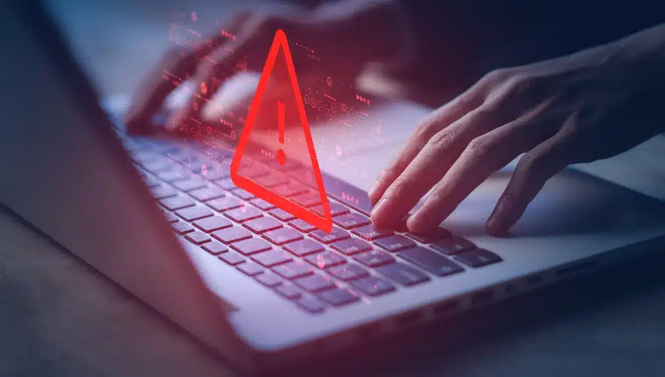 A flashing warning sign over a laptop computer.