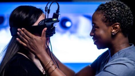 Two diverse individuals interact with advanced eye-tracking technology, highlighting innovation in healthcare education while embracing diversity.