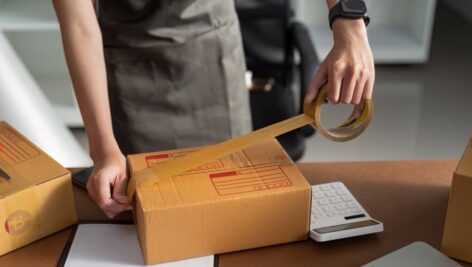 A man taping a mail parcel closed.