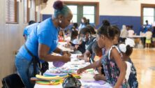 adult helping children with arts and crafts