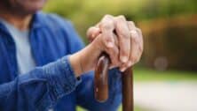 An elderly man holding a cane.