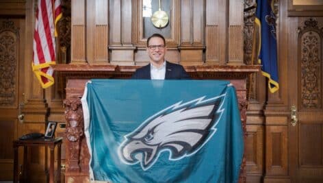 Josh Shapiro holding up an Eagles flag in the State capitol.