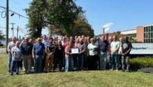 The staff of Superior Tube gathered outside in front of sign.