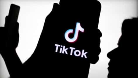 A silhouette of a phone with TikTok on the display.