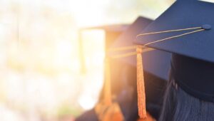 The back image of the graduates wearing a yellow tassel hat.