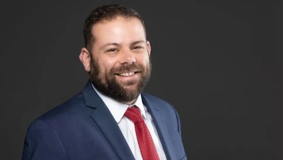 Headshot of attorney with blue suit and red tie.