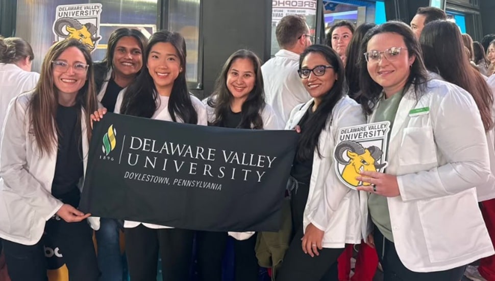 College students pose for group photo with banner.