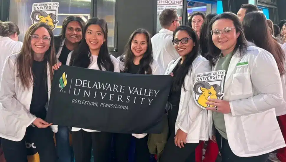 College students pose for group photo with banner.