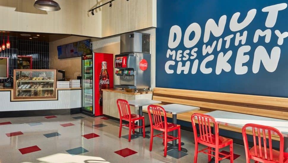 The inside of a Federal Donuts & Chicken shop showing a counter, chairs, tables and a sign.
