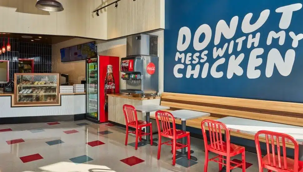 The inside of a Federal Donuts & Chicken shop showing a counter, chairs, tables and a sign.