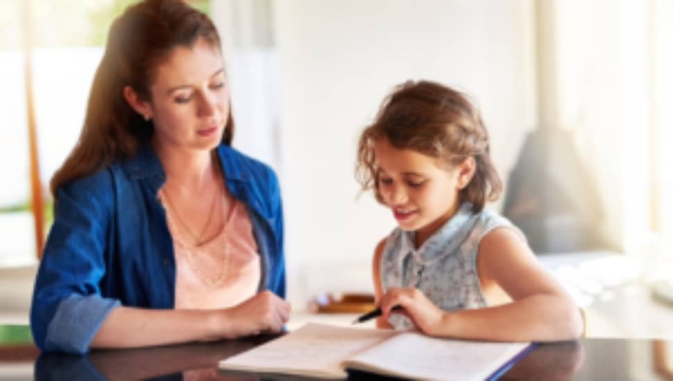 A mom helps her young daughter with her growth journal.
