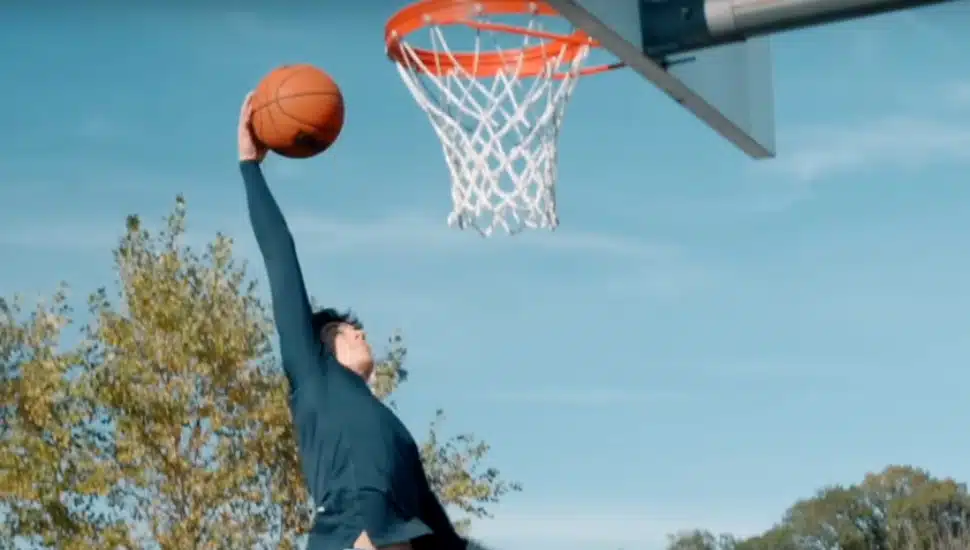 Jake West reaching to dunk a basketball.