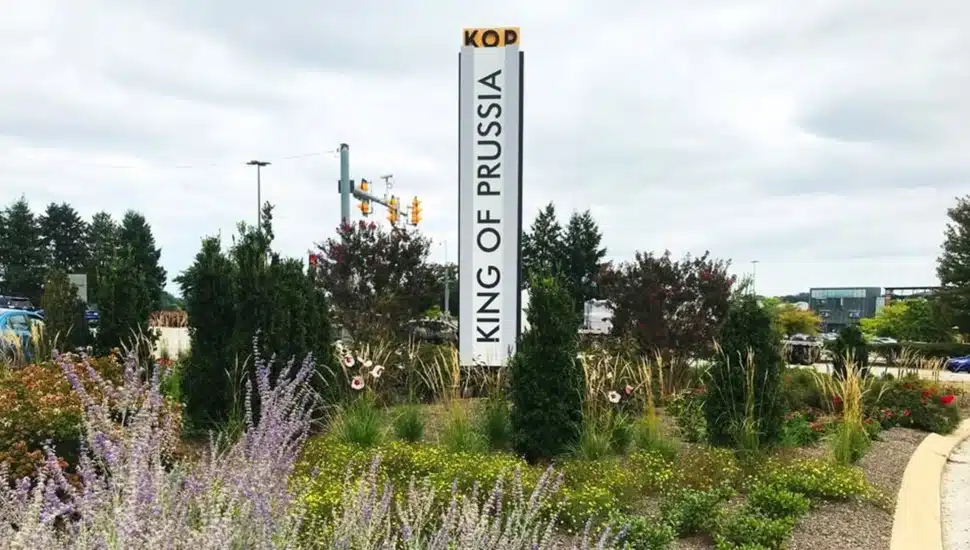King of Prussia road sign surrounded by grass and trees.