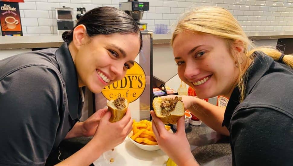 Two female employees eat food from Nudy's Cafe.