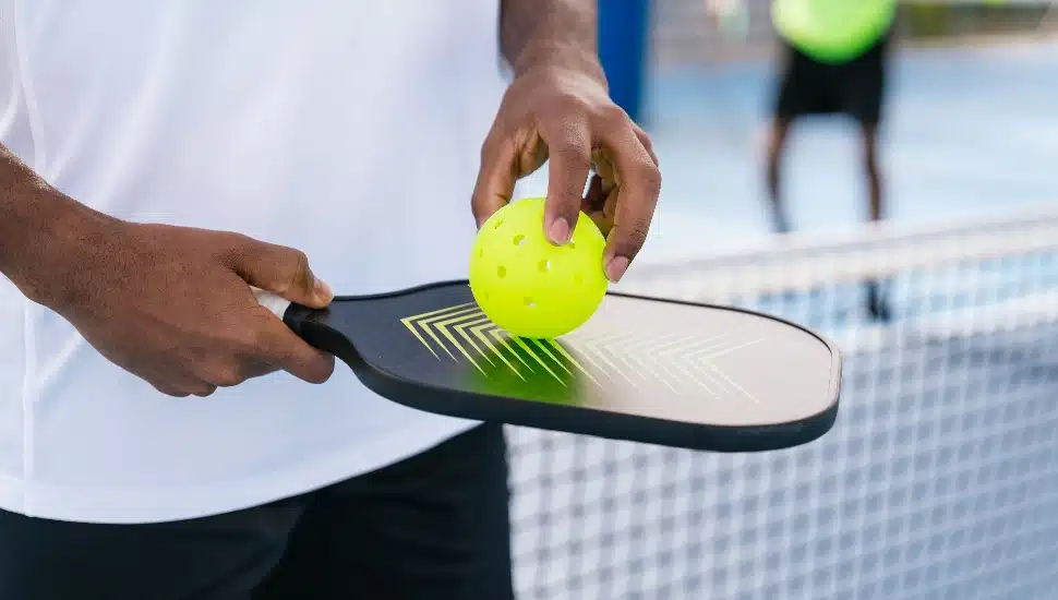 A player ready to serve on a pickleball court.