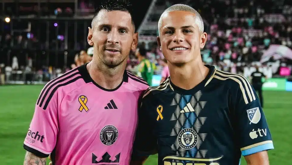 Cavan Sullivan poses with Lionel Messi on the pitch.