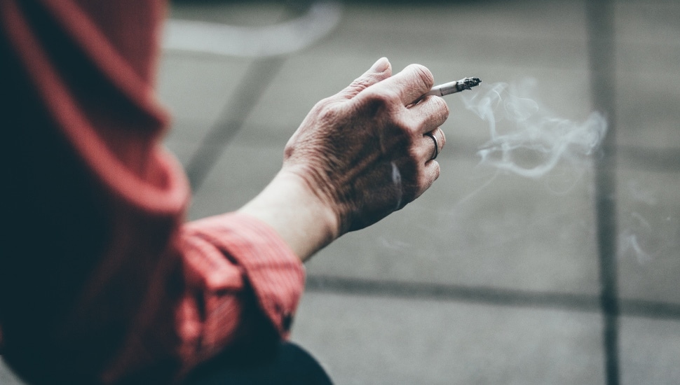 A man holding a lit cigarette.