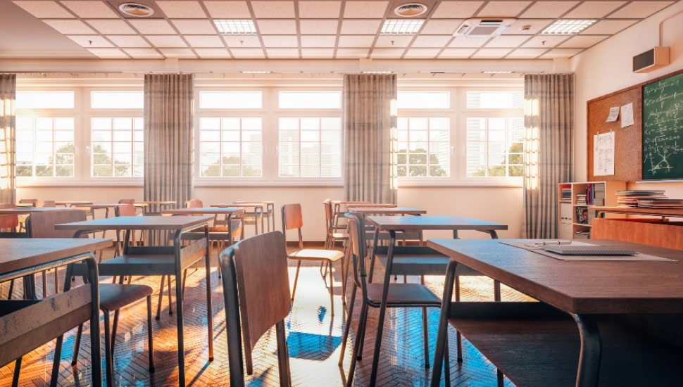 The inside of an empty classroom with desks and a chalkboard.