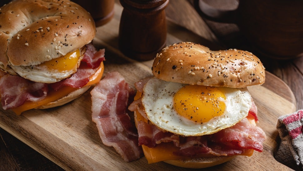two breakfast sandwiches on a board.