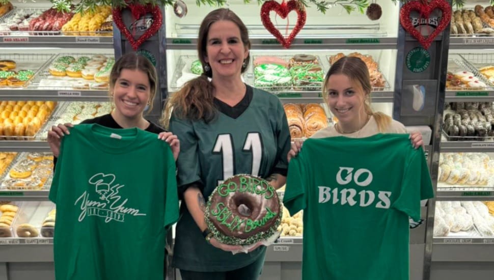 Three customers holding a 'Go BIrds' donut.