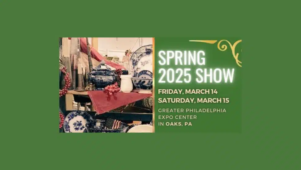 A promotional graphic for the Spring 2025 Antique & Collector Fair in Oaks, PA. The left side features a display of blue and white antique china, decorative items, and American flags arranged on a table with a red cloth. The right side has bold white and yellow text on a green background, announcing the event dates as Friday, March 14, and Saturday, March 15, at the Greater Philadelphia Expo Center in Oaks, PA. The design includes elegant gold flourishes in the top corner.