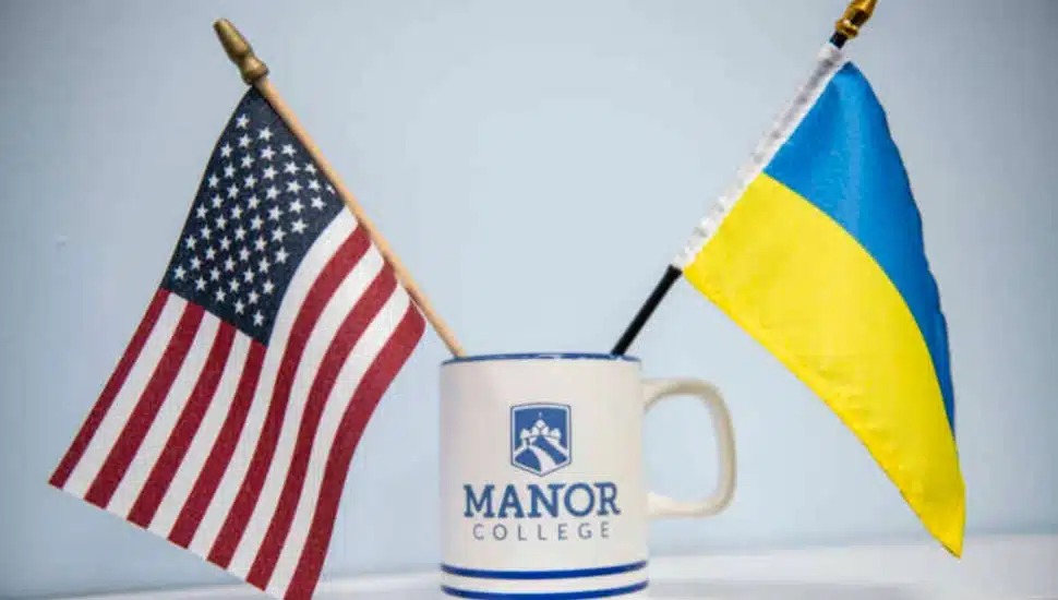 A Ukrainian flag and an American flag in a Manor College coffee cup.