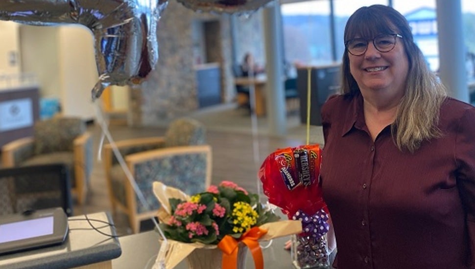 Woman celebrates 45 years working at bank with balloons and flowers.