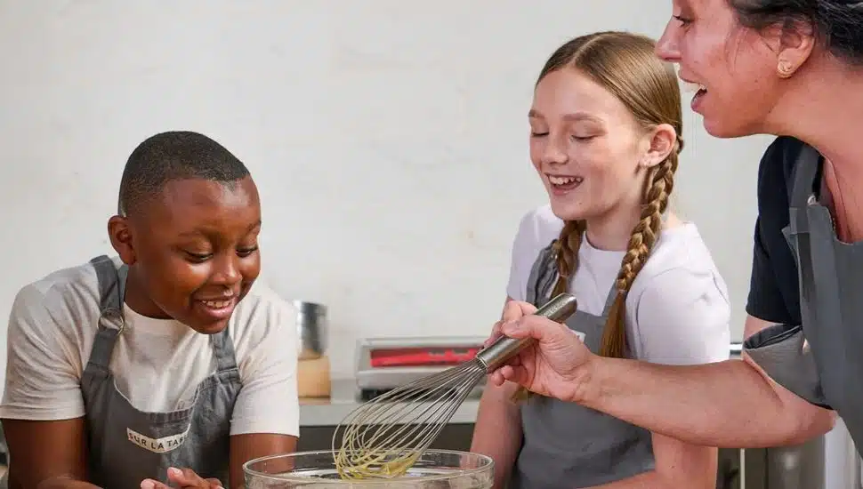 A cooking instructor whisking batter with two children.