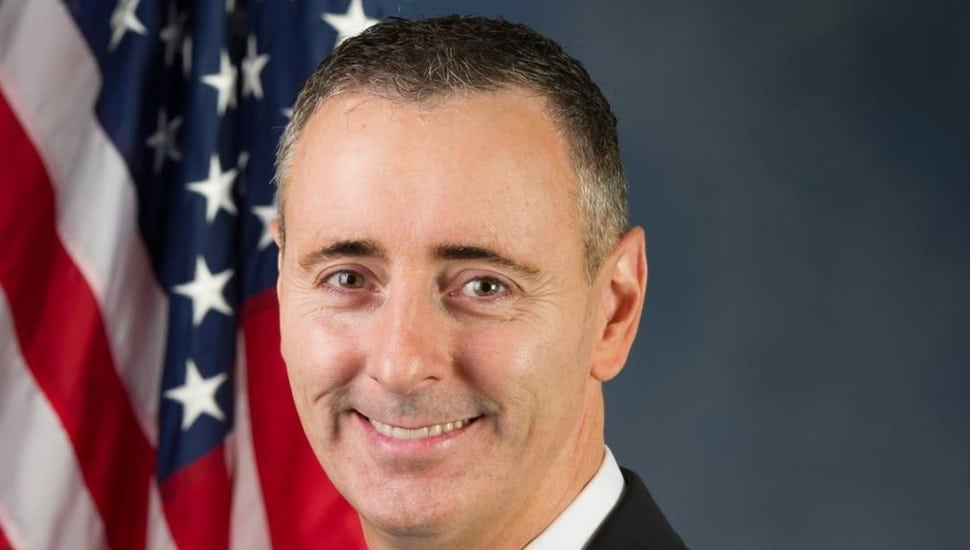 Brian Fitzpatrick smiling with an American flag in the background.