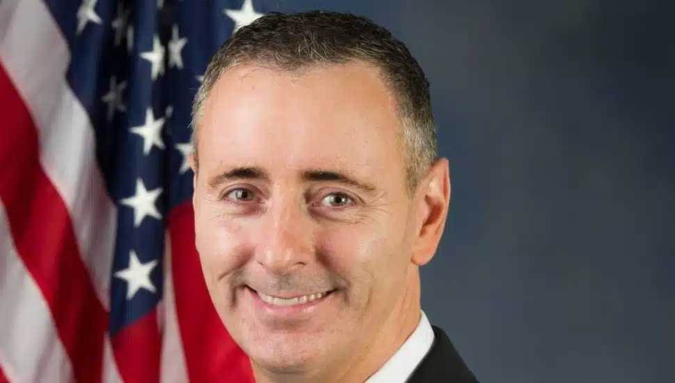 Brian Fitzpatrick smiling with an American flag in the background.