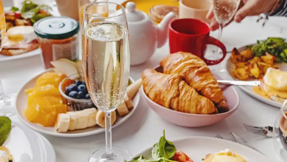 A brunch table with mimosas, croissants, and fruit.