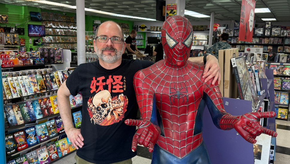 Brave New Worlds owner Eric Loyack posing with Spider-Man statue.