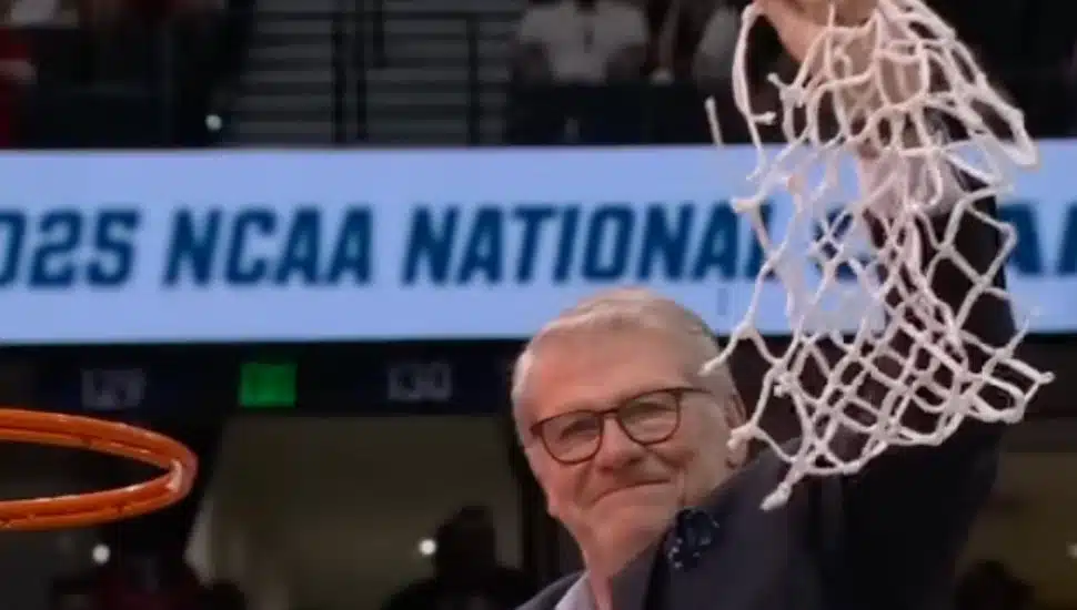 Geno Auriemma holds up the net after cutting it from the basket.