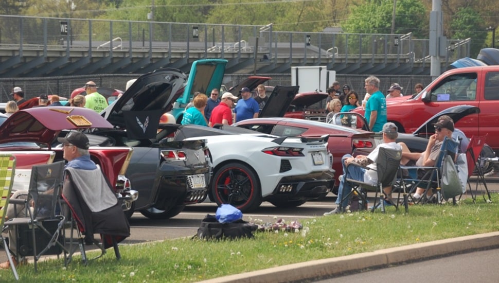 View of car show with people sitting in folding chairs.