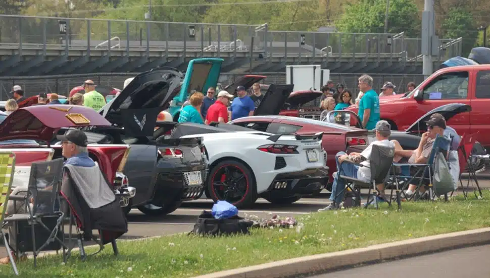 View of car show with people sitting in folding chairs.