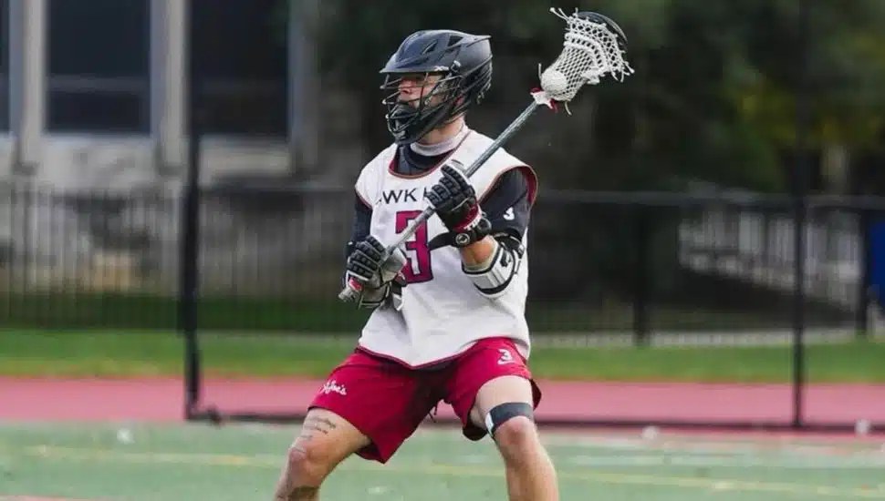 Richie LaCalandra on the field in uniform, holding a lacrosse stick.