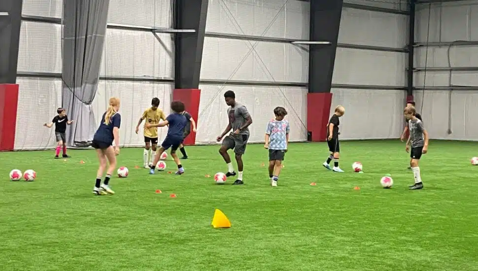 A soccer coach running drills with child athletes at the Select Soccer Center.