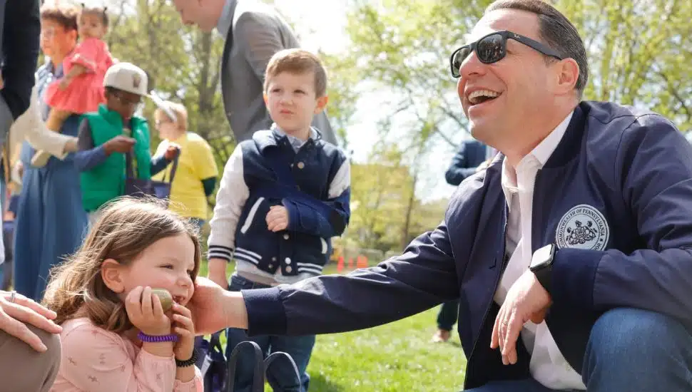 Governor Josh Shapiro kneels down with a young girl at the Easter Egg Hunt.