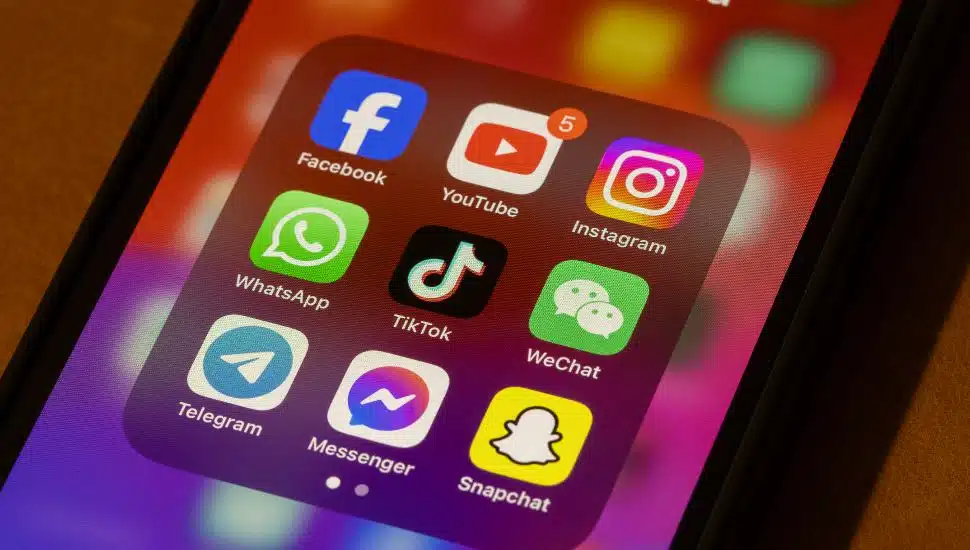 A smartphone displaying social media apps including TikTok, Facebook, Instagram, and Snapchat.