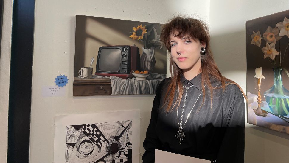 Hailey Kutt standing next to her piece, “Television Still Life.”
