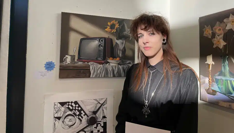 Hailey Kutt standing next to her piece, “Television Still Life.”