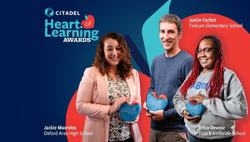 Three teachers hold awards in front of bank signage.