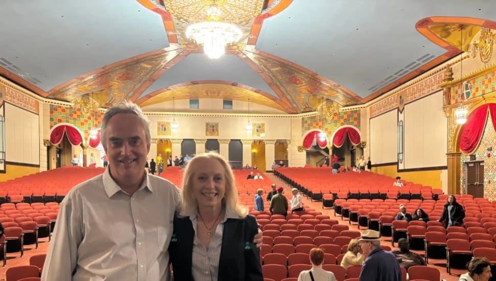 The beautiful restoration of the 1927 Lansdowne Theater can be seen in the background. Matt Schultz of the Historic Lansdowne Theater Corp. stands on stage with U.S. Rep. Mary Gay Scanlon .
