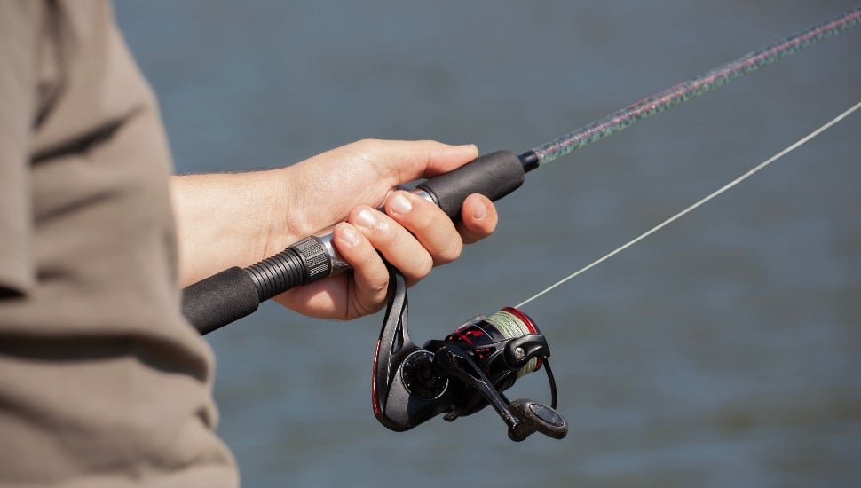 A hand holding a fishing reel.