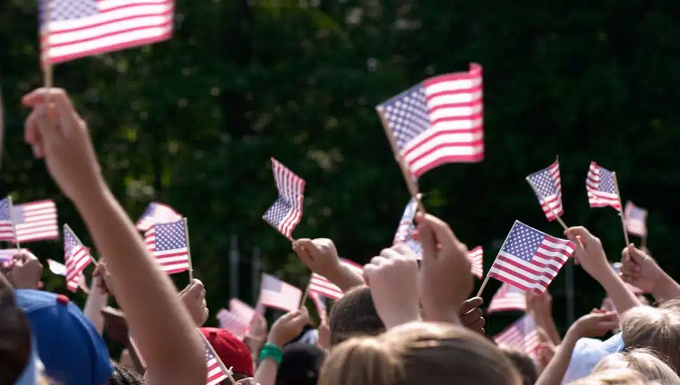 Hands holding USA flags over a crowd.