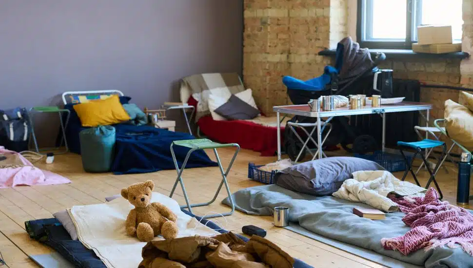 Part of spacious room with sleeping places on wooden floor for refugees or temporarily homeless people because of war or cataclysm.