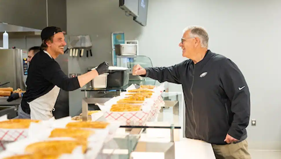 Bradley Cooper fist bumps Vic Fangio over the counter.
