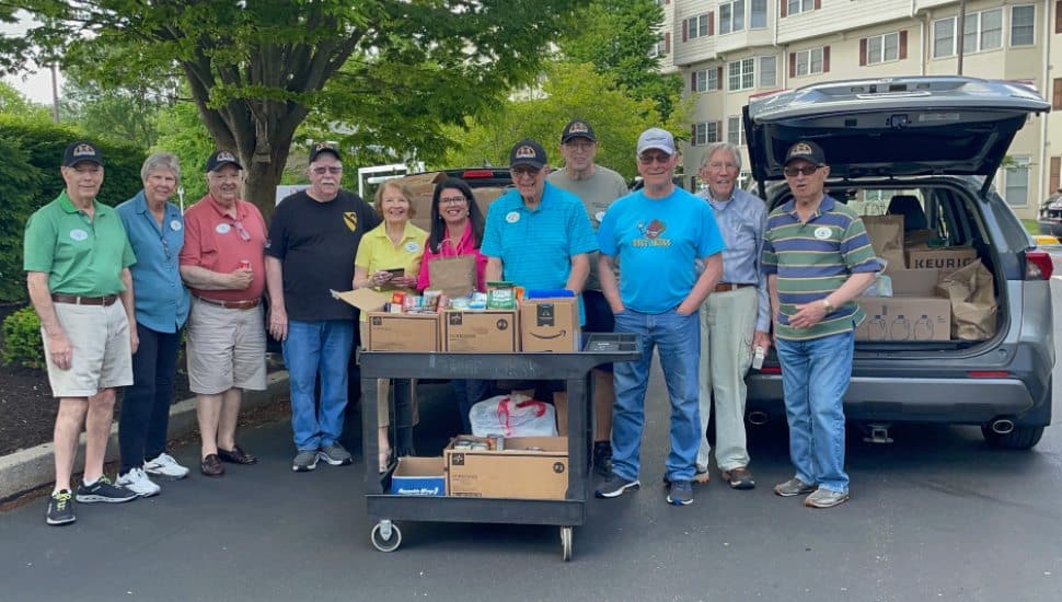 Freedom Village residents stand with some of the 1,500 donated food items collected for veterans.