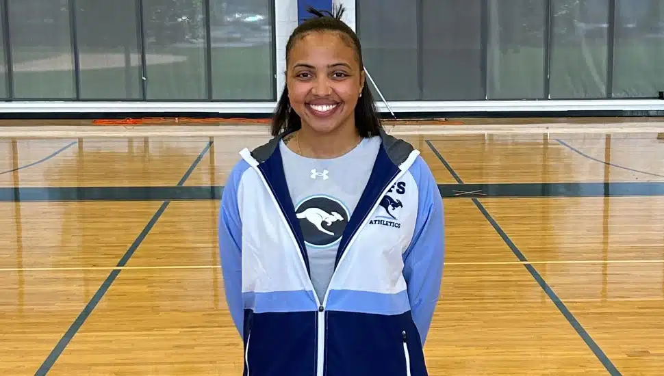 Young female basketball coach in white and blue jacket.
