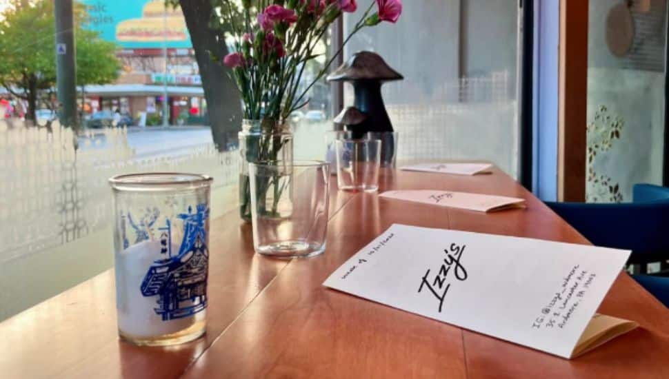 An Izzy's menu and cocktail glass resting on a window-side table.